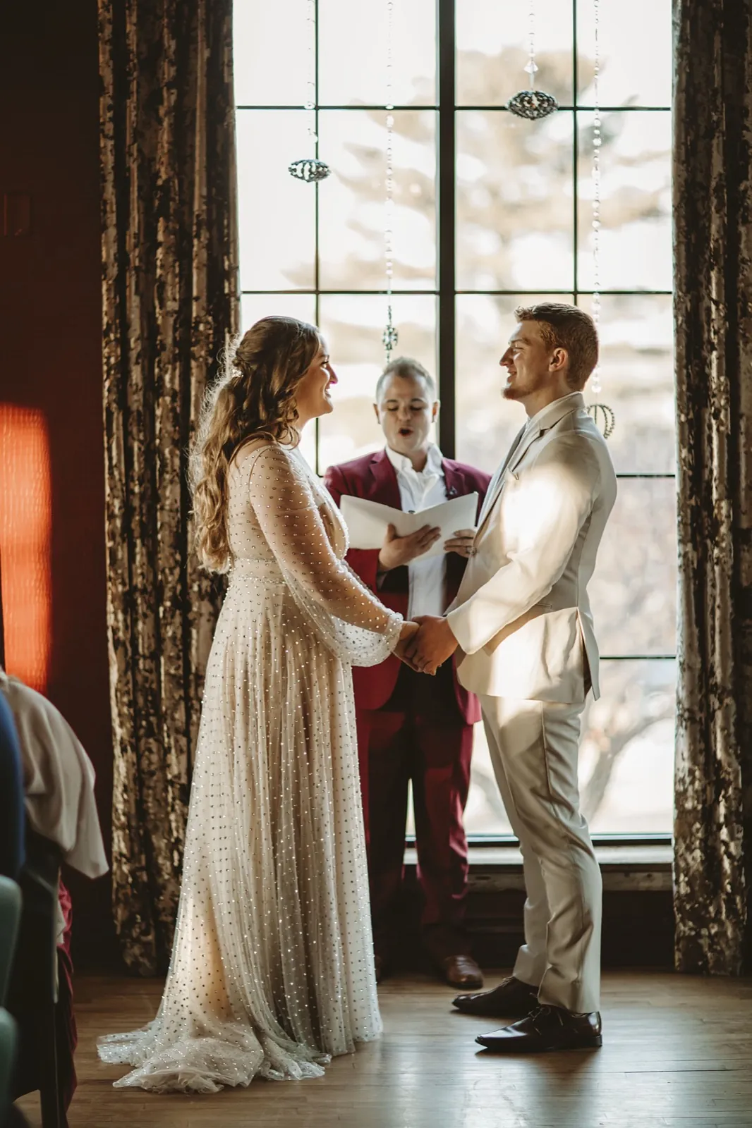 Wedding ceremony by dramatic window light with officiant Schwa Potter