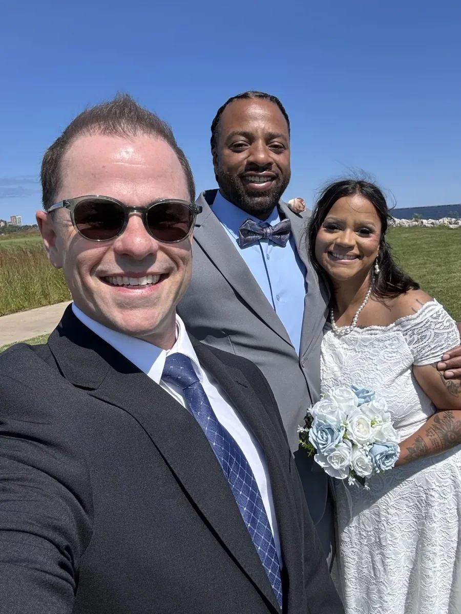 Wedding officiant Schwa Potter selfie with couple outdoors on sunny day